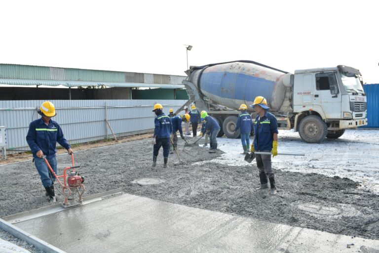 Importance of Compaction and Types of Concrete Vibrators Team of workers pouring cement from a mixer truck on a construction site, ensuring proper leveling.